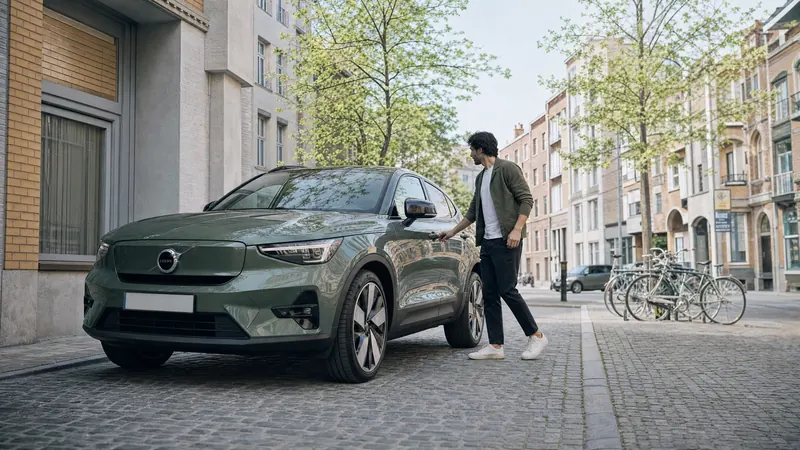 Iemand stapt in een groene Volvo EX40 op een geplaveide stadsstraat, met fietsen in een rek langs de stoep